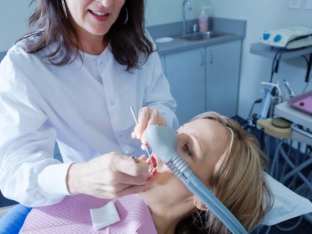 picture of woman in dental chair receiving sedation while dentist works on mouth