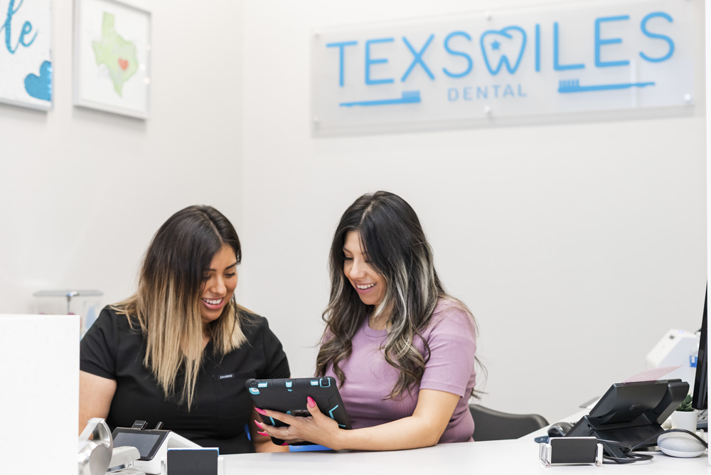 team members of texsmiles dental working at the front desk looking at ipad