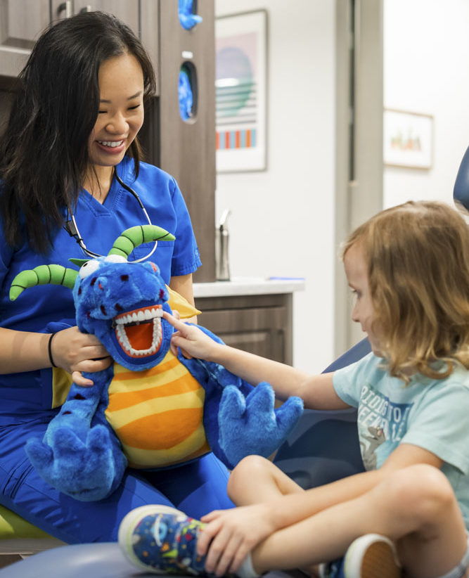 dr pamela liu of texsmiles dental showing child in dental chair a stuffed animal with teeth