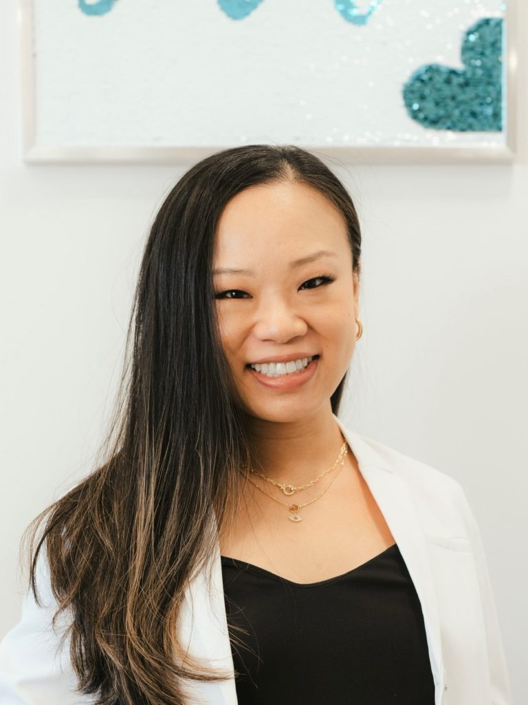 Dr. Pamela Liu, a professional dentist, smiles confidently in her dental office, showcasing her expertise and dedication.