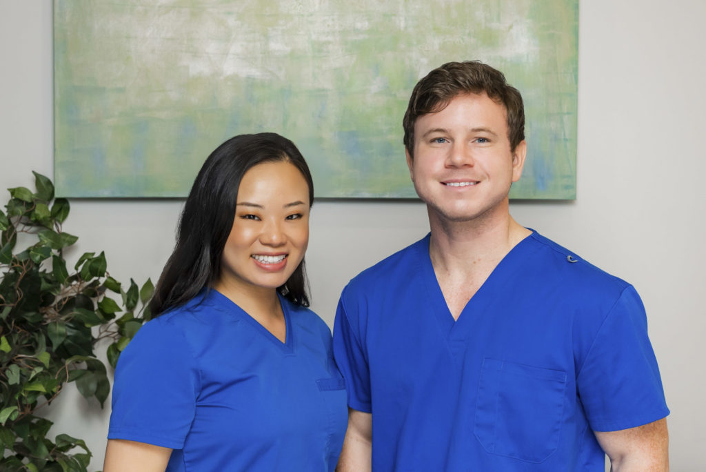 Dr. Pamela Liu and Dr. Juston Reary wearing blue scrub suits, exuding warmth and professionalism in Texsmiles dental office.